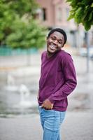 Young african american man in violet jumper posed against fountain alley. photo