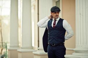 Portrait of retro 1920s english arabian business man wearing dark suit, tie and flat cap. photo