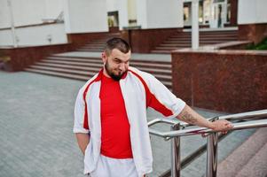 Young brutal bearded muscular man wear on white sport suit with red shirt. photo