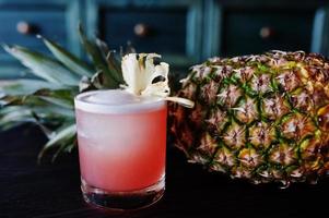 Alcoholic cocktail with pineapple at bar table. photo