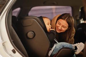 Young mother and child in car. Baby seat on chair. Safety driving concept. photo