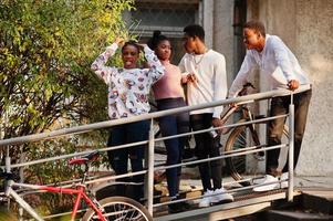 Four african friends walking the streets of an ancient city with bilkes. photo