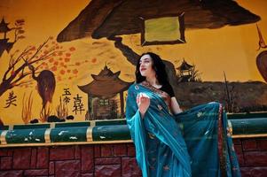 Portrait of beautiful indian brumette girl or hindu woman model against japanese grafiti wall. photo