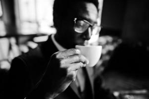 Close up hand of african american business man holding cup of coffee and drink it. photo