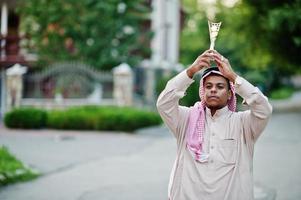 hombre de negocios árabe del medio oriente posó en la calle con una copa de oro en las manos. foto
