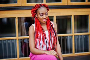 Fashionable african american girl at pink pants and red dreads posed outdoor. photo