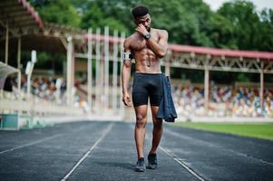 African american male athlete sexy sport bare torso man with running sports arm case for mobile phone, posed at stadium. photo