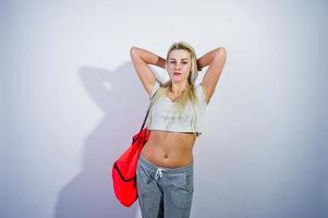 Chica rubia deportiva con una gran bolsa deportiva posada en el estudio con fondo blanco. foto