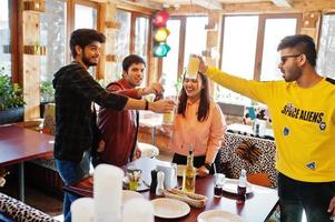 Group of asian friends sitting cafe. Happy indian people having fun together and cheers by glasses of juice. photo