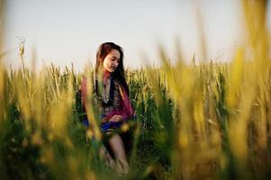 Tender indian girl in saree, with violet lips make up posed at field in sunset. Fashionable india model. photo