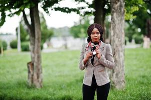 Young african american female doctor hold white coat on hand with a stethoscope posed outdoor. photo