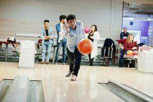 South asian man in jeans shirt standing at bowling alley and throw ball in air. photo