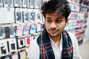 Indian man customer buyer at mobile phone store sitting on chair. South asian peoples and technologies concept. Cellphone shop. photo