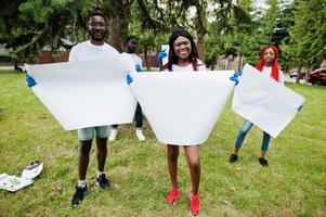 un grupo de voluntarios africanos felices sostiene un tablero en blanco vacío en el parque. Concepto de voluntariado, caridad, personas y ecología de África. espacio libre para su texto. foto