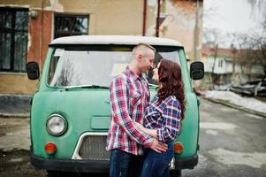 Stylish couple wear on checkered shirt in love together against old minivan. photo