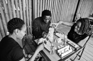 Group of three african american friends play table games. photo