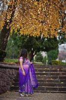 Indian hindu girl at traditional violet saree posed at autumn street. photo