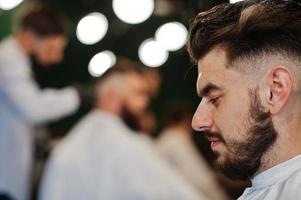 apuesto hombre barbudo en la barbería, peluquero en el trabajo. foto