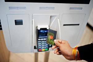 Hands of man customer at store place orders and pay by contactless credit card through self pay floor kiosk for fast food, payment terminal. Pay pass. photo