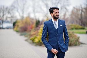 hombre indio de barba elegante con bindi en la frente, vestido con traje azul posado al aire libre. foto