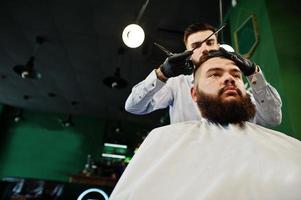 apuesto hombre barbudo en la barbería, peluquero en el trabajo. foto