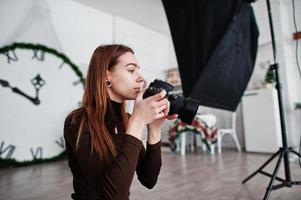 Young girl photographer shooting on studio. Professional photographer on work. photo