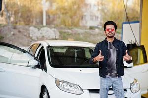 South asian man or indian male washing his white transportation on car wash. photo