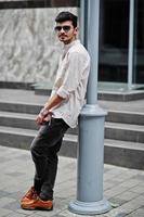 Stylish indian model man in casual clothes and sunglasses posed outdoor at street of India. photo