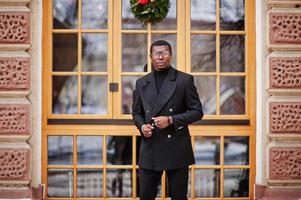 elegante caballero afroamericano con elegante chaqueta negra. rico hombre afro de moda contra la ventana. foto