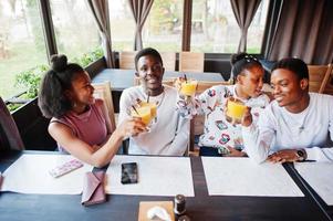 Happy african friends sitting and chatting in cafe. Group of black peoples meeting and cheers in restaurant. photo