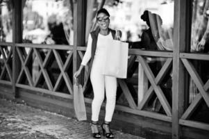 Casual african american girl with colored shopping bags walking outdoor. Stylish black woman shopping. photo