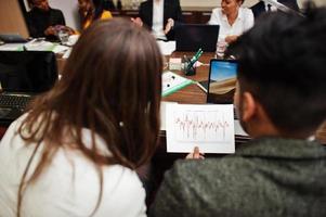 equipo de negocios multirracial que aborda la reunión alrededor de la mesa de juntas. foto