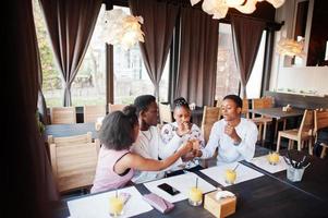 Happy african friends sitting and chatting in cafe. Group of black peoples meeting and play games by hands in restaurant. photo