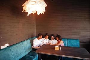 felices amigos africanos sentados y charlando en el café. grupo de personas negras reunidas en un restaurante. foto