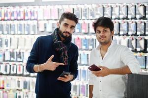 Two indians mans customer buyer at mobile phone store with them new smartphones. South asian peoples and technologies concept. Cellphone shop. photo