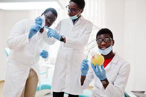 tres colegas médicos afroamericanos en clínica dental con una manzana. foto