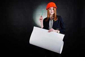 Engineer woman in orange protect helmet with construction paper projekt. photo