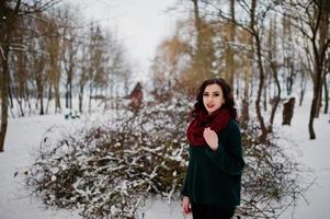 Brunette girl in green sweater and red scarf outdoor on evening winter day. photo