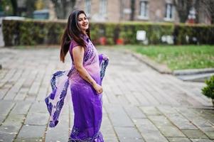 Indian hindu girl at traditional violet saree posed at autumn street. photo