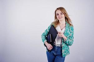 Stylish blonde girl in jacket and jeans with notebook diary and laptop at hands against white background on studio. photo