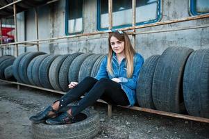 Young hipster girl in jeans jacket and head scarf at tire fitting zone. photo