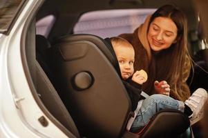 Young mother and child in car. Baby seat on chair. Safety driving concept. photo