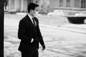 Concept of coronavirus quarantine. Business man wear on suit with medical face mask and mobile phone at hand. MERS-Cov, Novel coronavirus 2019-nCoV photo