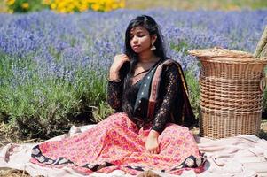 hermosa niña india usa vestido tradicional saree india en campo de lavanda púrpura. foto