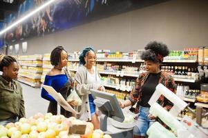 Group of african womans weighs apples in polyethylene bags at supermarket. photo