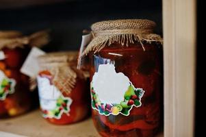 frascos de vidrio con diferentes tipos de mermelada y bayas de los estantes de un supermercado o tienda de comestibles. productos de conservas caseras. hecho con amor. foto