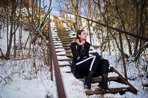 Fashionable long legs brunette model in long black cloak posed outdoor at winter day. photo