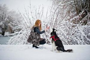 chica pelirroja caminando en el parque con perro husky en día de invierno. foto