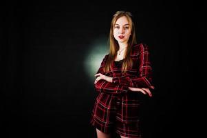 Young blonde girl in checkered dress at black background. photo