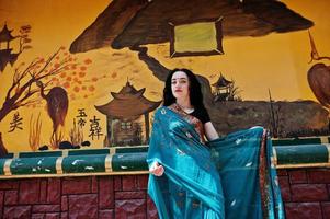 retrato de una hermosa brumette india o modelo de mujer hindú contra una pared de grafiti japonesa. foto